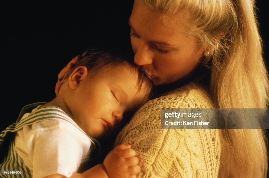 Mother holding sleeping baby (3-6 months)