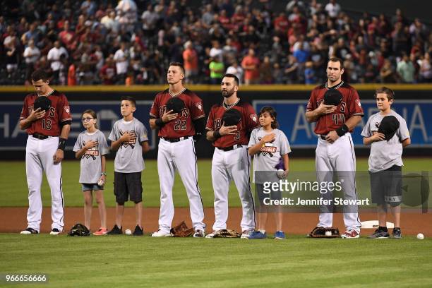 Nick Ahmed, Jake Lamb, Daniel Descalso and Paul Goldschmidt of the Arizona Diamondbacks stand for the national anthem with Smile Generation kids for...