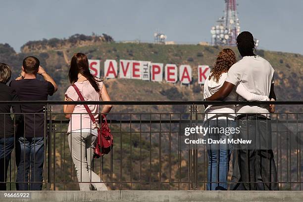 Visitors to the Hollywood and Highland complex view the iconic 450-foot-long Hollywood sign after activists covered it with banners during an effort...