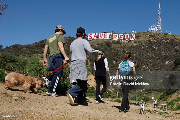 Hikers pass near the iconic 450-foot-long Hollywood sign after activists covered it with banners during an effort to prevent the building of houses...