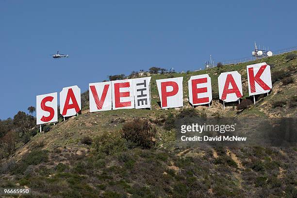 Helicopter flies over the iconic 450-foot-long Hollywood sign after activists covered it with banners during an effort to prevent the building of...