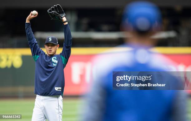 Hisashi Iwakuma of the Seattle Mariners stretches while throwing on the field before a game against the Tampa Bay Rays at Safeco Field on June 3,...