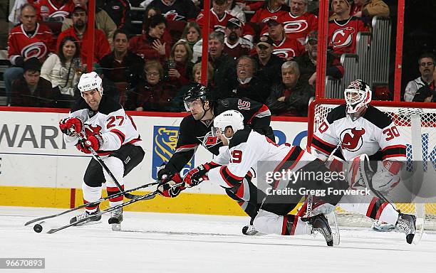 Tuomo Ruutu of the Carolina Hurricanes battles for the puck against Travis Zajac and Mike Mottau of the New Jersey Devils during a NHL game on...