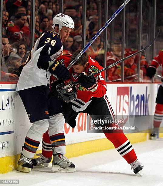 Tomas Kopecky of the Chicago Blackhawks looses his helmut as he battles for the puck with Eric Boulton of the Atlanta Thrashers along the boards at...