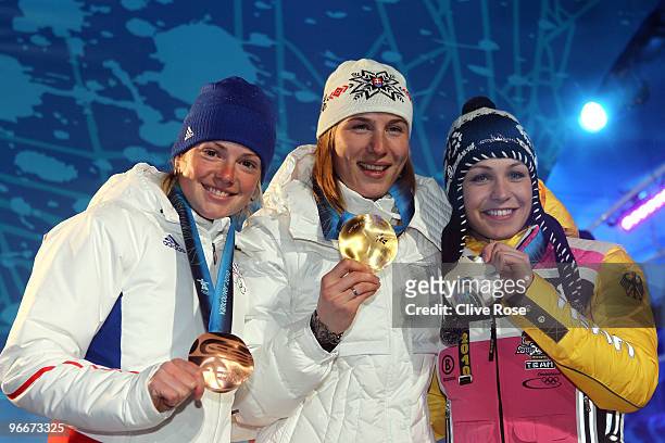 Anastazia Kuzmina of Slovakia celebrates with the gold medal, silver medalist Magdalena Neuner of Germany and bronze medalist Marie Dorin of France...