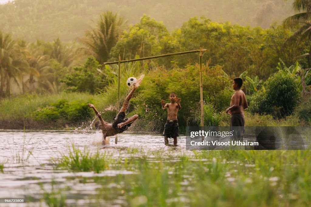 Children playing football in the river.
