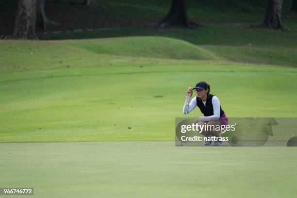 vrouwelijke golfer op één lijn staat haar lange putt - golf putter stockfoto's en -beelden