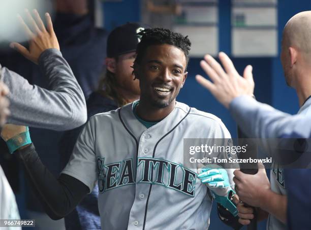 Dee Gordon of the Seattle Mariners is congratulated by teammates in the dugout after scoring a run in the first inning during MLB game action against...