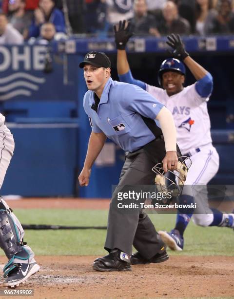 Home plate umpire Quinn Wolcott gets ready to make the call at home plate as Russell Martin of the Toronto Blue Jays runs home to score a run as...