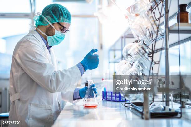 男性的生物技術專家，在實驗室中測試新的化學物質。 - beaker 個照片及圖片檔