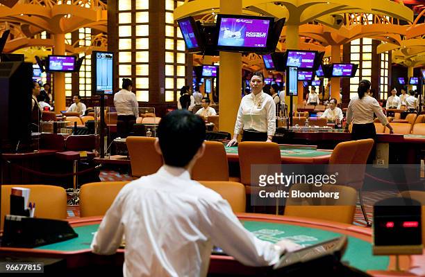 Casino workers stand ready to receive the first gamblers at the soft opening of Genting Singapore Plc's Resorts World Sentosa casino in Singapore, on...