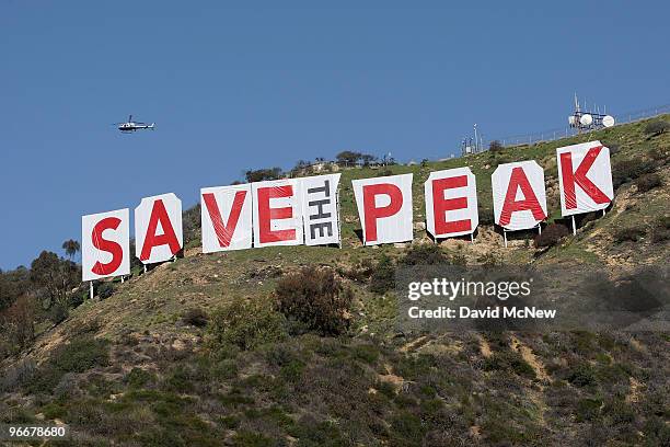 Helicopter flies over the iconic 450-foot-long Hollywood sign after activists covered it with banners during an effort to prevent the building of...