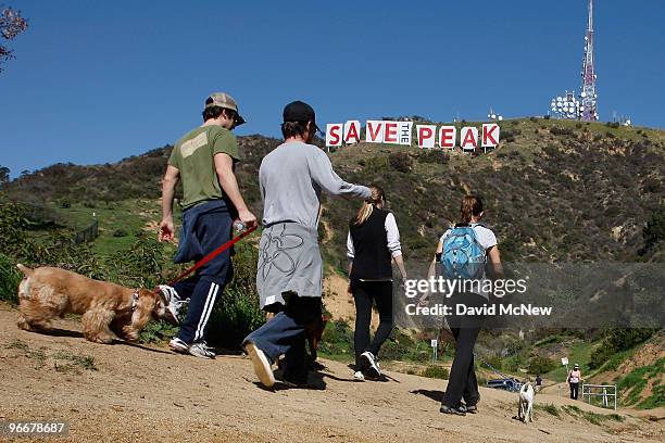 Hikers pass near the iconic 450-foot-long Hollywood sign after activists covered it with banners during an effort to prevent the building of houses...