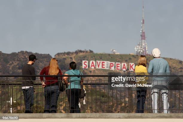 Visitors to the Hollywood and Highland complex view the iconic 450-foot-long Hollywood sign after activists covered it with banners during an effort...