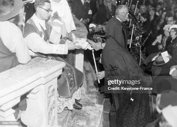 Une Provençale fait ses dévotions à l'Enfant Jésus durant la messe de minuit aux Baux-de-Provence, France le 25 décembre 1932.