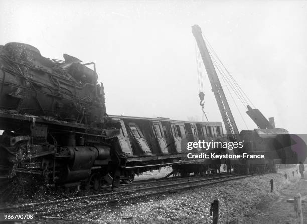 Un wagon accidenté est retiré des voies par une grue, à Pomponne, France le 23 décembre 1933.