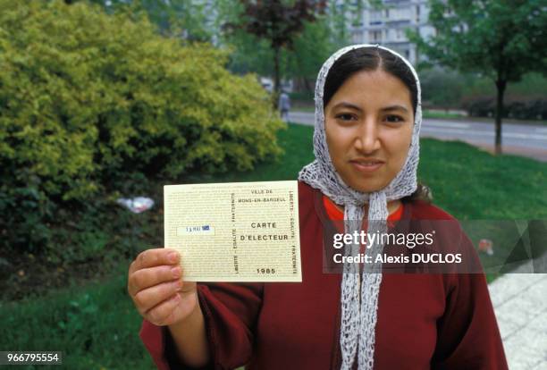 Une immigrée maghrébine montre sa carte électorale le 19 mai 1985 à Mons-en-Baroel, France.