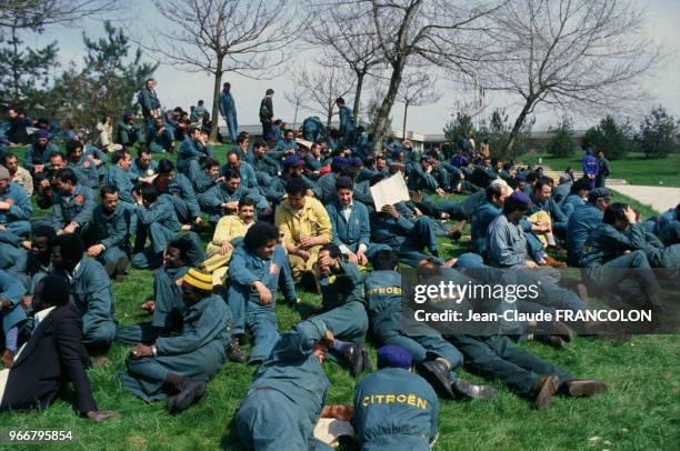 Les ouvriers grévistes de l'usine Citroen assis sur les pelouses en signe de protestation le 18 avril 1984 à Aulnay-sous-Bois, France.