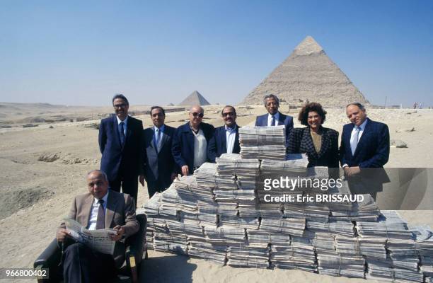 Le PDG Ibrahim Nafeh du journal égyptien 'Al-Ahram' assis devant les pyramides avec en arrière plan ses collaborateurs le 18 mars 1990 au Caire,...