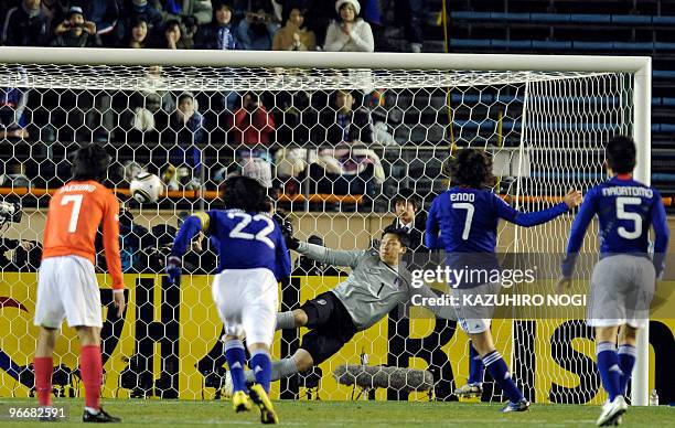 Japan's midfielder Yasuhito Endo scores a goal against South Korea's goalkeeper Lee Woo Jae as he shoots a penalty kick during their match of the...