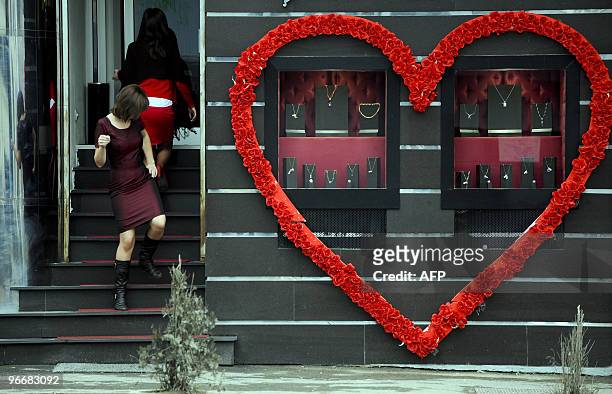 Young woman passes by a jewellery store decorated with a heart in Pristina on February 14, 2010. Valentine's Day, celebrated on February 14, is named...