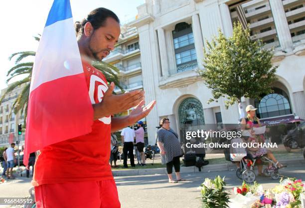 Un homme avec un drapeau français et portant un tee-shirt turque se recueille et prie sur la promenade des Anglais après l'attentat terroriste du 14...