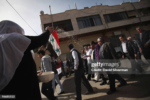 Druze woman throws rice as residents of the Golan Heights rally with a Syrian flag in support the Damascus regime on February 14, 2010 in Majdal...