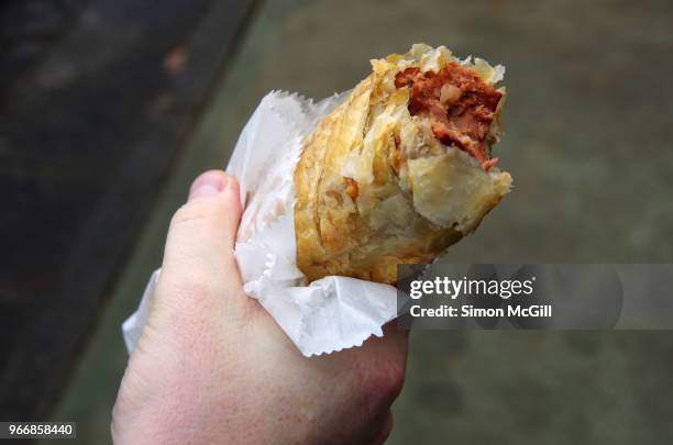 man's hand holding a cheese kransky (carniolan) sausage roll in a white paper bag - sausage roll stock pictures, royalty-free photos & images