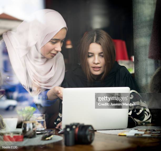 Two Muslim girls in coffeeshop using laptop
