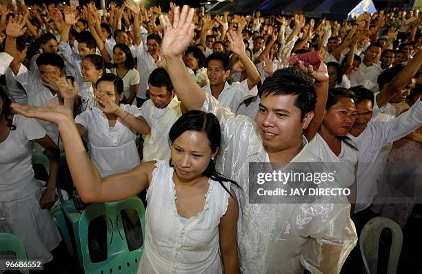 Newly-wed couples wave after being pronounced husband and wife at a mass Valentine's Day wedding ceremony in Caloocan City suburb of Manila on...