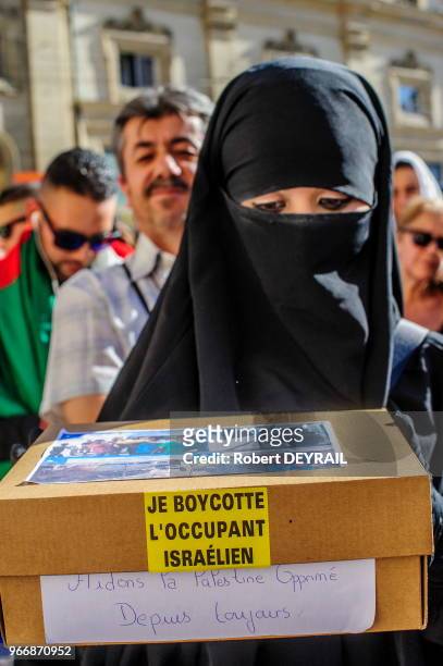 Manifestante voilée portant une boite en carton avec l'inscription 'Je boycotte l'occupant israélien' lors d'un rassemblement devant l'Hotel de ville...