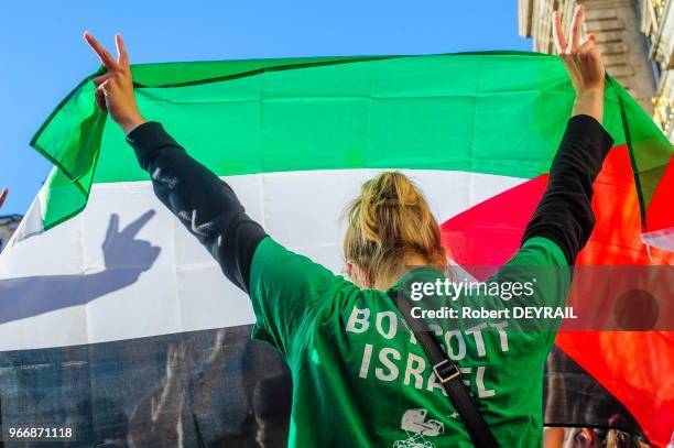 Manifestante de dos levant le drapeau palestinien et portant un tee-shirt 'Boycott Israël' lors d'un rassemblement devant l'Hotel de ville en signe...