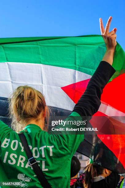 Manifestante de dos levant le drapeau palestinien et portant un tee-shirt 'Boycott Israël' lors d'un rassemblement devant l'Hotel de ville en signe...