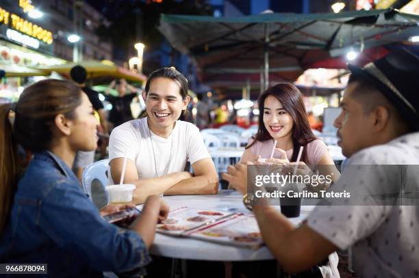friends sitting around an outdoor restaurant table with drinks - malaysian culture stock-fotos und bilder