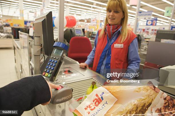 Employee Nicole Lohn watches a customer pay by fingerprint inside a Real store, owned by Metro AG, in Toenisvorst, Germany, on Friday, Feb. 12, 2010....