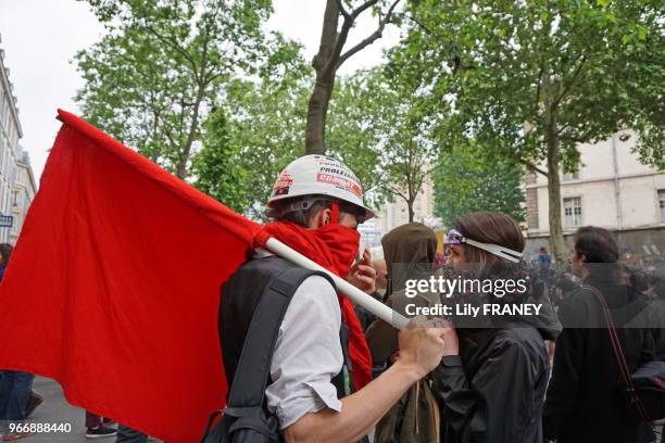 Jeunes gens avec le visage caché et portant un drapeau rouge lors de la manifestation contre la loi travail dite 'Loi El Khomri', le 26 mai 2016,...