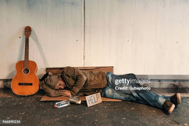 sans-abri affamé et dormir sur une rue avec l’enseigne - beggar photos et images de collection