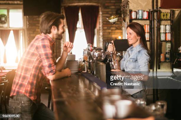 female bartender serving beer to a costumer - costumer stock pictures, royalty-free photos & images