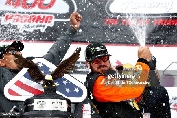 Martin Truex Jr., driver of the Bass Pro Shops/5-hour ENERGY Toyota, celebrates with champagne in Victory Lane after winning the Monster Energy...