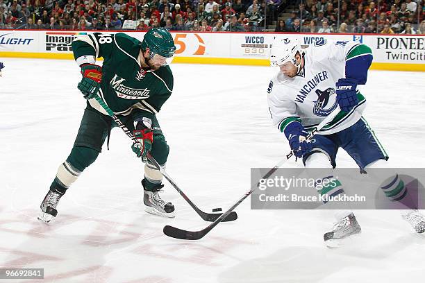 Guillaume Latendresse of the Minnesota Wild and Steve Bernier of the Vancouver Canucks fight for control of a loose puck during the game at the Xcel...
