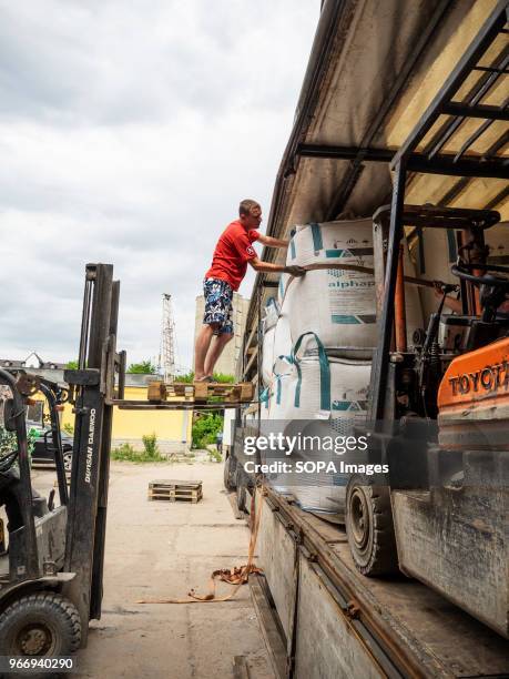 Man seen on top of a forklift while loading big bags with crushed plastic bottles into the truck to be sent for further processing. In Ukraine,...