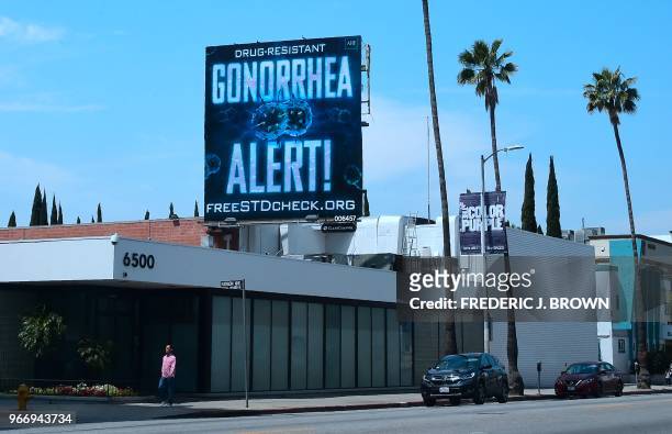 Pedestrian walks along Sunset Boulevard in Hollywood, California on May 29, 2018 beneath a billoard from the AIDS Healthcare Foundation warning of a...