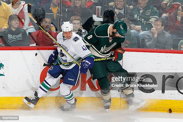 Brent Burns of the Minnesota Wild and Kyle Wellwood of the Vancouver Canucks collide while skating to the puck during the game at the Xcel Energy...