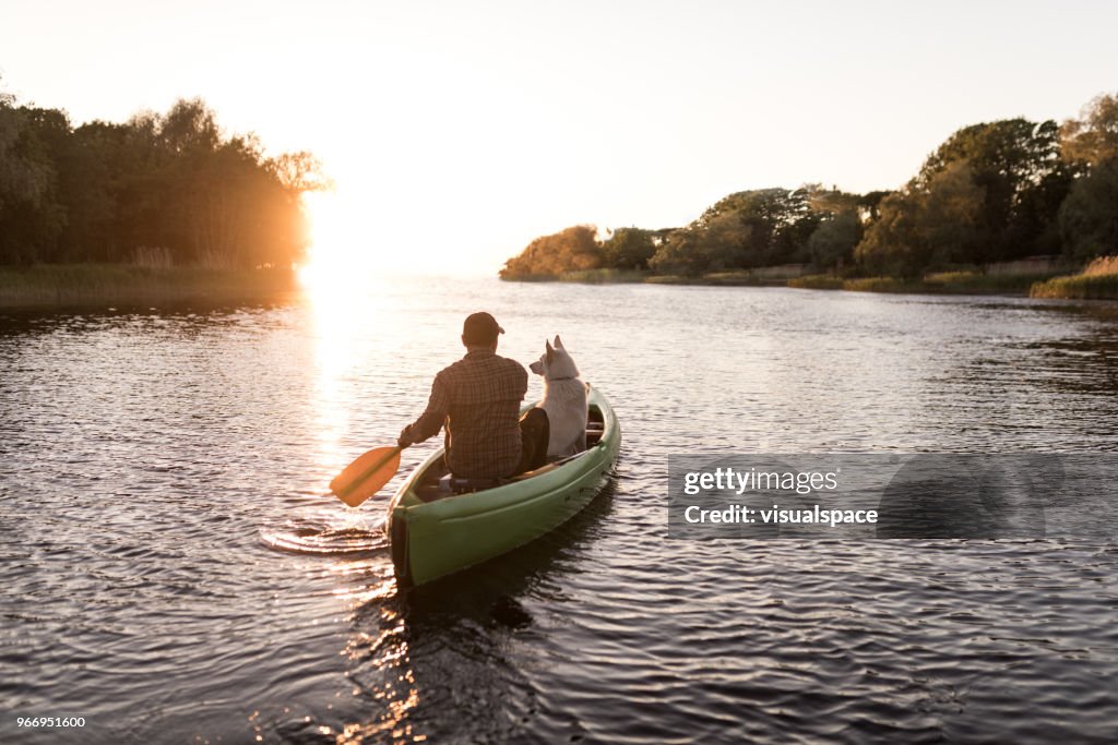 Man and dog in the sun set with canoe