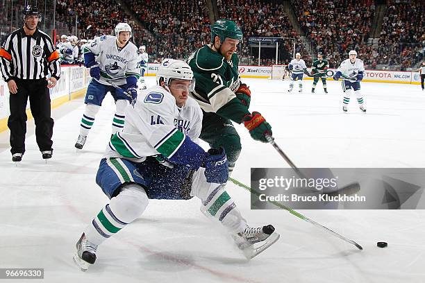 Kyle Brodziak of the Minnesota Wild and Nolan Baumgartner of the Vancouver Canucks battle for control of the puck during the game at the Xcel Energy...