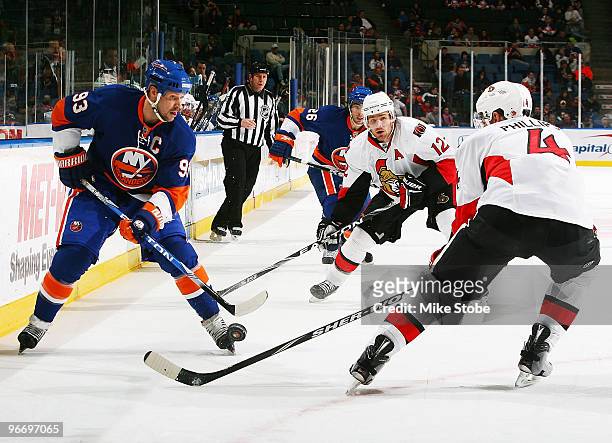 Chris Phillips of the Ottawa Senators battles for the puck against Doug Weight of the New York Islanders on February 14, 2010 at Nassau Coliseum in...