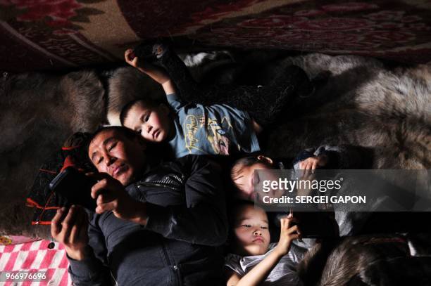 Reindeer herder and children use gadgets inside a tent in the remote Yamalo-Nenets region of northern Russia on March 6, 2018.
