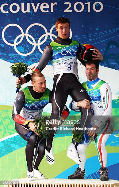 Gold medallist Felix Loch of Germany is held aloft by silver medallist David Moeller of Germany and bronze medallist Armin Zoeggeler of Italy after...