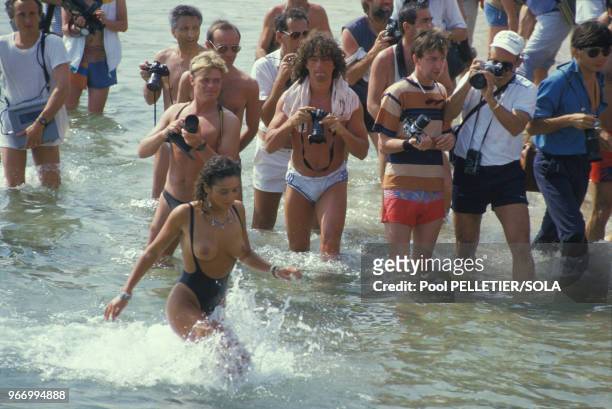 Une starlette topless sort de l'eau sous l'objectif des photographes au Festival de Cannes le 16 mai 1986, France.
