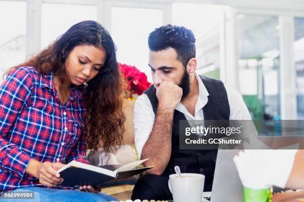 empresario teniendo en cuenta ventas diarias de su colega - arab businesswoman with books fotografías e imágenes de stock